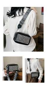 Detailed close-up of a black crossbody camera bag with silver studs and woven strap