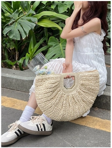 Detail of hand-woven straw tote bag with integrated handle shown in outdoor resort setting