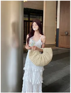 Detailed view of a semi-circular straw tote bag with a white lace ruffled sundress
