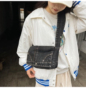 Detailed view of black denim bag with contrast stitching and Y2K rivet style