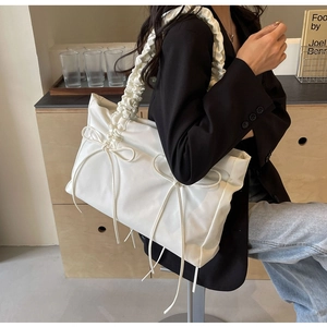 Detail van witte shopper met geplooide schouderband en subtiele strikdecoraties