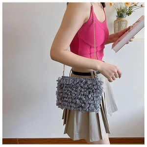 Detail of grey ruffled mesh crossbody bag with gold chain strap on a model shoulder