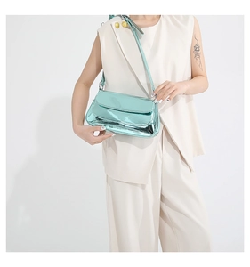 Glossy mint green baguette bag with adjustable strap worn on a beige suit