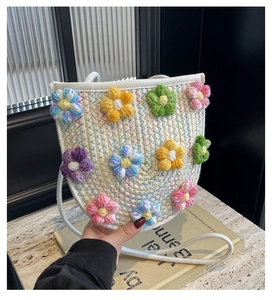 Detail of hand-woven crossbody bag featuring colorful 3D crochet flowers and soft knit texture