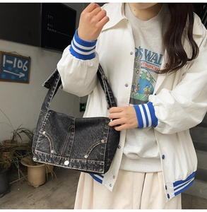 Detail of vintage washed denim shoulder bag with metal rivets and decorative stitching