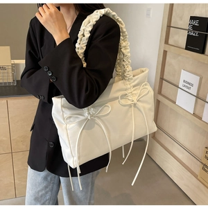 Detail van beige shopper tas met geplooide schouderbanden en decoratieve strikken