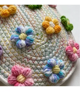 Detail of handmade woven white cotton fabric with colorful crochet flower decorations