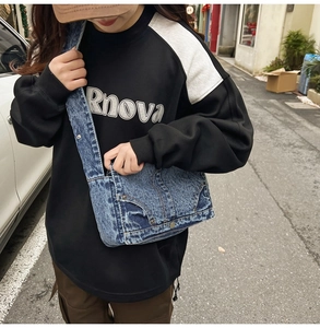 Detail of blue washed denim shoulder bag with vintage frayed edges and metal buttons