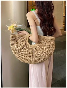 Back view of a model carrying a large woven straw tote bag in a stylish room