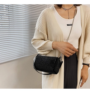 Detail of a black rhinestone cylindrical crossbody bag with chain and leather straps