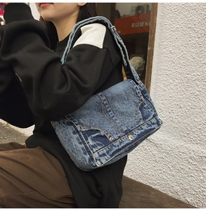 Detail of vintage denim shoulder bag featuring classic stitching and metal button accents