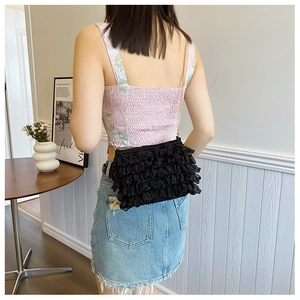 Close-up of black mesh tiered ruffle crossbody bag with a slim gold chain shoulder strap