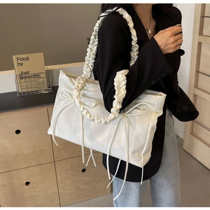 Detail van witte geplooide shopper met decoratieve dubbele strikken en wolkvormige banden
