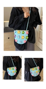 Detailed view of hand-knitted light blue crossbody bag with 3D colorful floral patterns