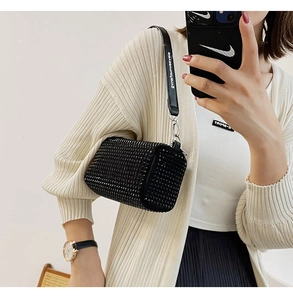 Detail of black rhinestone baguette bag with branded shoulder strap on female model