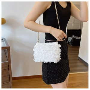 Détail du sac à bandoulière en maille blanche avec une chaîne dorée élégante