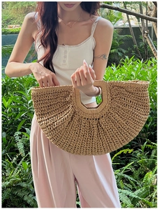 Detail of woven straw handbag featuring an integrated hollow handle and natural texture