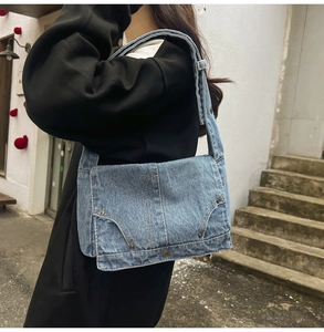 Detail of vintage washed denim shoulder bag with metal studs and flap closure