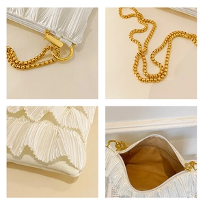 Detail view of white pleated shoulder bag showing satin texture, gold chain and inner pocket