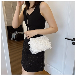 Sac à bandoulière blanc plissé avec chaîne dorée porté par un mannequin dans un intérieur