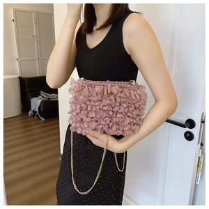 Detail of pink pleated fabric crossbody bag with mesh layers and delicate gold chain strap