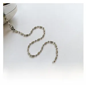 Detailed close-up of a silver bead chain strap with a spring metal clasp on the bag