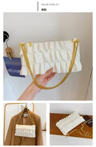 Detail of off-white pleated shoulder bag featuring elegant golden double chain straps