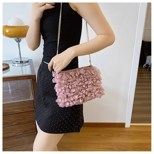 Détail du petit sac carré rose à volants en maille avec bandoulière en chaîne dorée