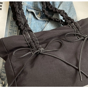 Detailopname van zwarte nylon tas met geplooid ontwerp en witte contrasterende stiksels