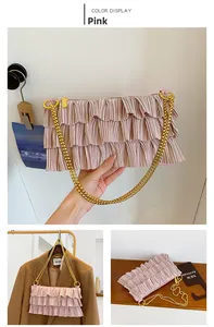 Close-up of pink pleated ruffle texture with a bold gold chain strap on shoulder bag