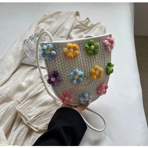 Detail of hand-woven saddle bag featuring 3D colorful crochet flowers and white cord strap