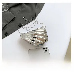 Detail of silver shell-shaped acrylic clutch with bead chain against a gray blazer