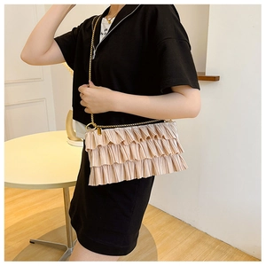 Detail of champagne pleated ruffle shoulder bag with gold chain strap on model