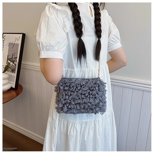 Close-up of gray mesh woven crossbody bag with gold chain strap on model