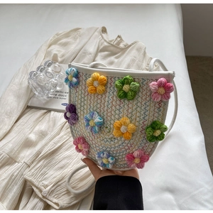 Detail of colorful 3D crochet flowers on a white woven bucket bag with rope strap