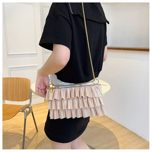 Detail of champagne pleated shoulder bag with layered ruffles and gold chain strap