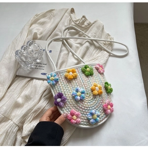 Detailed knit texture of a white crochet crossbody bag with colorful floral embroidery