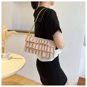 Detail of beige tiered ruffle shoulder bag with gold chain strap shown on model