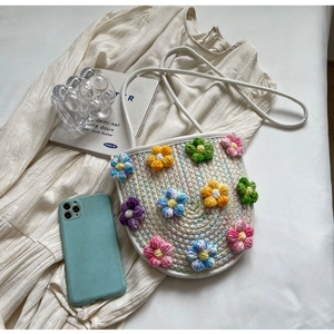 Detail of white woven crossbody bag with colorful knitted 3D flowers in pastoral style