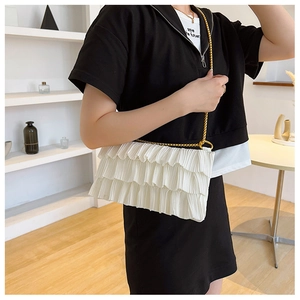 Detailed view of the white ruffled shoulder bag featuring three-layered design and gold chain