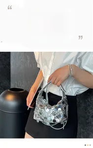 Detail of silver sequin handbag with pearl strap against minimalist outfit and dark background
