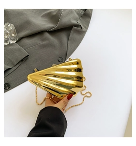 Close-up of golden shell-shaped clutch bag with polished metallic mirror finish and chain