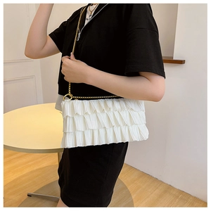 Detail of white pleated shoulder bag with fine texture and golden metal chain strap