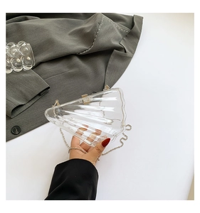 Detail of shell-shaped acrylic crossbody bag with wave texture and silver metal chain