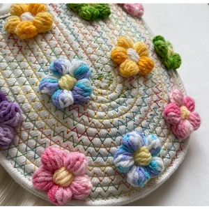 Detail of handcrafted floral crochet pattern on a white woven crossbody bag