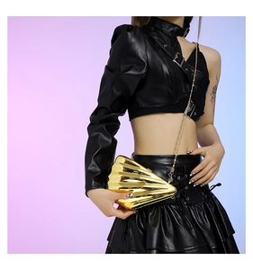 Detail of a gold seashell crossbody bag with textured waves and a sleek chain strap