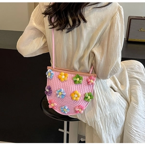 Close-up of pink woven crossbody bag featuring colorful handmade crochet flowers