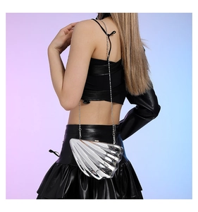 Close-up of a silver shell-shaped acrylic clutch with metallic chain on shoulder