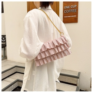 Detailed view of pink ruffled pleats and golden metal chain strap on shoulder bag