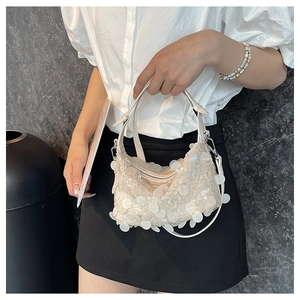Detail of white sequin handbag featuring glossy circular scales and silver metal buckle